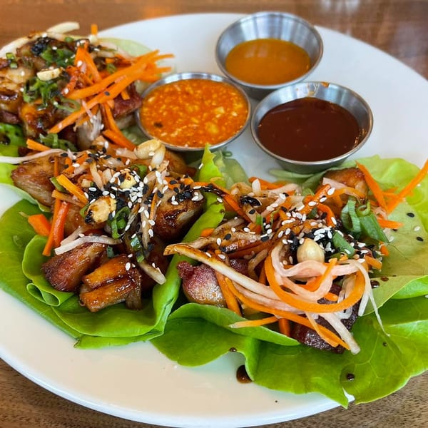Lettuce wraps filled with chicken, shredded carrots, and sesame seeds, served with three dipping sauces.